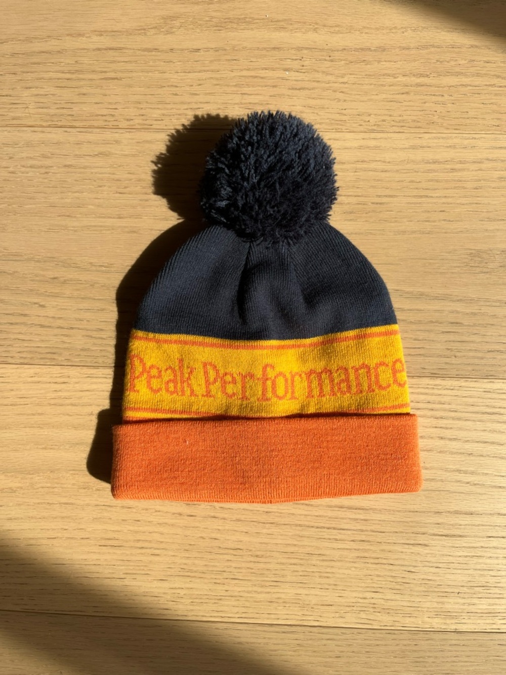Peak Performance Kids Pom Beanie in Navy, Yellow & Orange